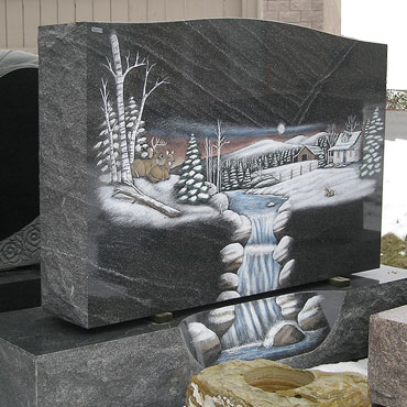 Moonlit wooded winter waterfall scene etched on tombstone memorial